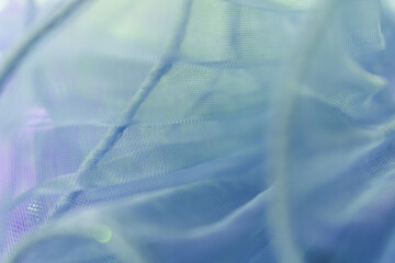 Softly draped light blue mesh fabric with delicate folds and semi-transparent texture, ideal for...