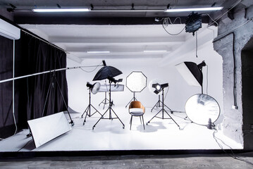 Well-equipped cyclorama photo studio featuring various lighting setups and props for professional photography sessions