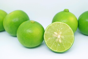 Row of vibrant green fresh lime scattered on white backdrop