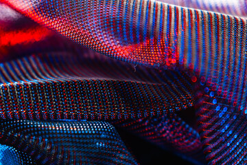 Vibrant close-up of draped textile with colorful dotted pattern, shimmering red, blue, and purple...