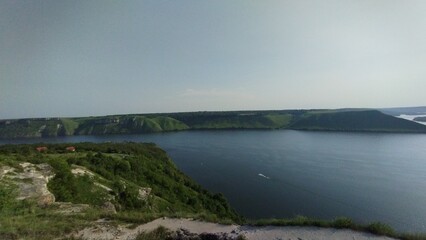 Naklejka premium Panoramic View of River and Green Cliffs under Clear Sky