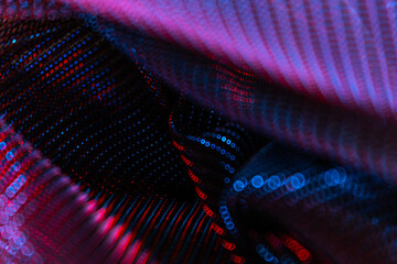 Abstract close-up of shimmering, metallic fabric with red and blue highlights, featuring intricate...