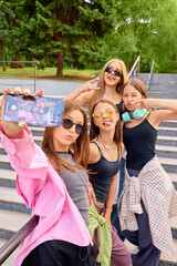 Youthful street dancers pose for a selfie on urban steps, showcasing stylish outfits and vibrant...