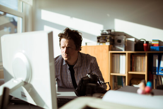Male photographer reviewing camera in creative office workspace
