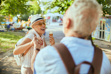 Senior couple laughing and eating ice cream at amusement park