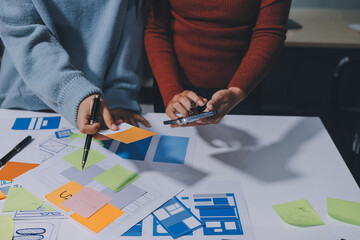UX UI designer testing prototype on a phone, discussing and brainstorming on wireframes for a...