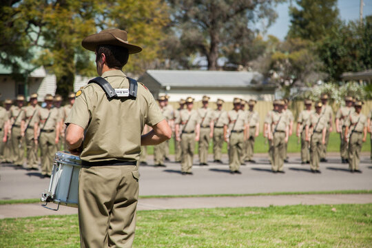 Army drummer playing in front of soldiers standing to attention