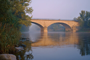 Fototapeta premium Historic Stone Arch Bridge Spanning a Serene River