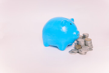 Financial Savings. Blue piggy bank and stack of coins isolated on white background. Investment...