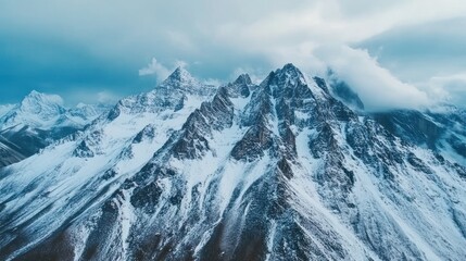 Obraz premium Majestic snow-capped mountain peaks pierce a dramatic sky. Vast, frosty peaks rise dramatically, blanketed in snow, under a moody sky