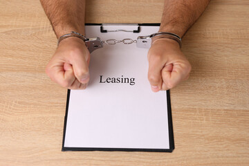 A man in handcuffs holds a document with the inscription 