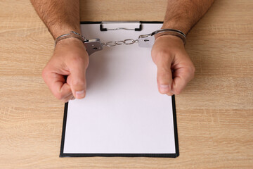 Man in handcuffs with a tablet with a blank sheet. Copy space on crime or addiction.