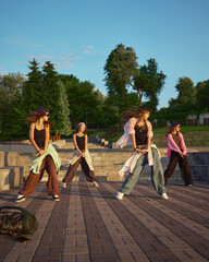 A street dance group performs an energetic routine in an urban park setting, showcasing diverse...