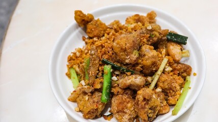 close up of Cantonese dish of deep fried salt and pepper squid  with garlic on a white plate