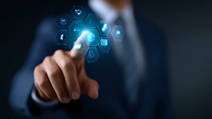 Fototapeta premium Businessman in dark suit touching virtual interface with glowing blue hexagonal icons, demonstrating digital transformation and future technology concept.
