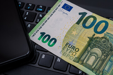 Notebook, Smartphone und 100 Eurogeldschein