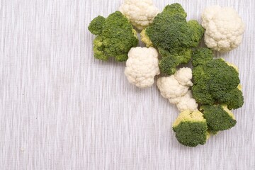 Top view of fresh broccoli and cauliflower florets on textile background with copy space
