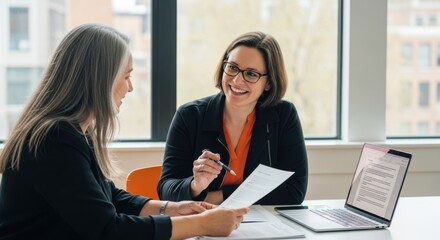 Two colleagues discuss a document in a bright office setting