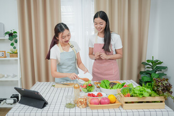 Asian young two women cooking salad in kitchen. Active beautiful girl feel happy and enjoy eating vegetables healthy foods to diet and lose weight for health care in house	