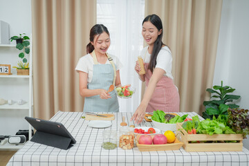 Asian young two women cooking salad in kitchen. Active beautiful girl feel happy and enjoy eating vegetables healthy foods to diet and lose weight for health care in house	