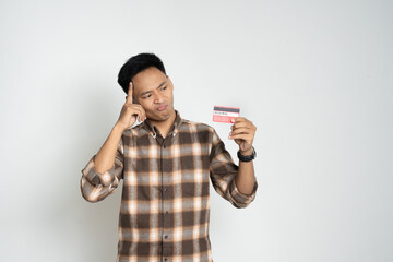 Young man in a brown plaid shirt looks shocked while holding a smartphone and credit card. Captures a concept of finance, online payment, digital transactions, and expressions of surprise or shock.
