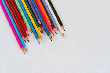 Flat lay of rainbow colored pencils arranged on a white background, ideal for back to school,...
