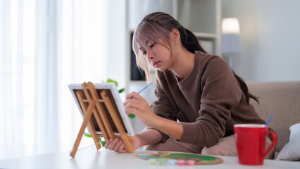 Young Asian Woman Focused on Canvas Painting at Home Art Time