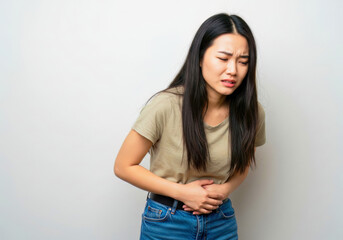 Gastric emergency: Asian female clutches her abdomen, plagued by severe flatulence, inflammation, and digestive upset at home.