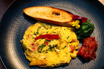 A plate presents a fluffy omelet, toast, and colorful garnishes for a delicious meal.
