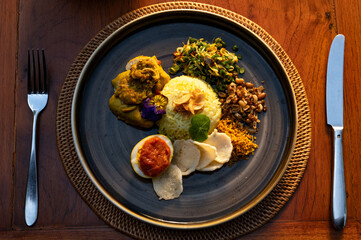 Indonesian Cuisine Turmeric Rice with Chicken Curry, Traditional Side Dishes, and Sunset Ambiance