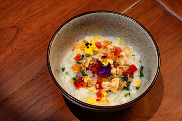 A small bowl of savory rice dish, garnished with colorful edible flowers and vegetables.