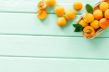 Collect apricots, green wooden background top view copy space, pattern with leaves