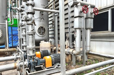 pipes and valves. Industrial electric motor pumps installed outdoors with connected pipelines and valves, used in cooling systems, HVAC, and fluid transfer operations in factories or energy plants.