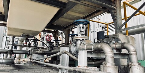 Close-up of stainless steel industrial piping system with valves and control components in a factory. Used in fluid transfer, process engineering, and manufacturing environments.