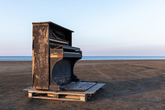 Old piano placed on wooden pallets in a serene beach setting