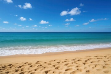A sandy beach with footprints in the sand and a blue sky