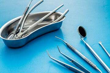 Dental instruments in stainless steel tray on blue background close up copy space