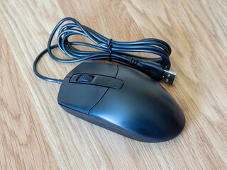 
New computer mouse with usb cable on a wooden background. Computer accessories. Ergonomic and...