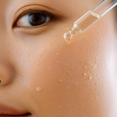 Fototapeta premium Close-up of Woman Applying Clear Serum with Dropper