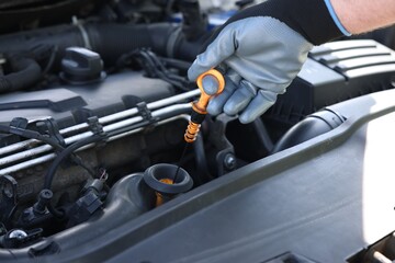 Worker checking motor oil level in car with dipstick, closeup