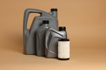 Motor oil in plastic canisters and filter on beige background, space for text