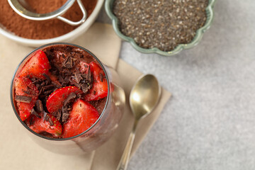 Delicious chocolate pudding with chia seeds and strawberries on light grey table, flat lay. Space for text