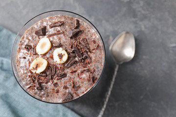 Delicious chocolate pudding with chia seeds and nuts in glass on grey table, top view. Space for text