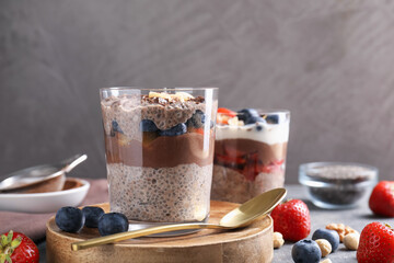 Delicious chocolate pudding with chia seeds, berries and hazelnuts in glasses on table, closeup