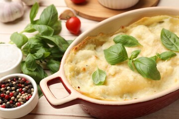 Tasty vegetarian lasagna and ingredients on wooden table, closeup
