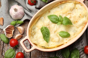 Tasty vegetarian lasagna and ingredients on wooden table, flat lay