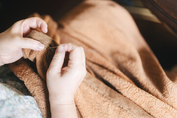 Asian elderly woman hand using sewing needle repair blanket Older people stay at home