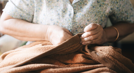 Asian elderly woman hand using sewing needle repair blanket Older people stay at home