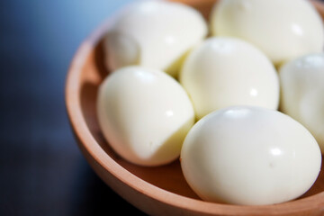 Closeup, Several boiled eggs in a wooden bowl on a black background
