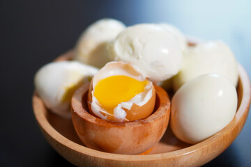 Closeup, Some whole boiled eggs and one half boiled egg in a wooden bowl